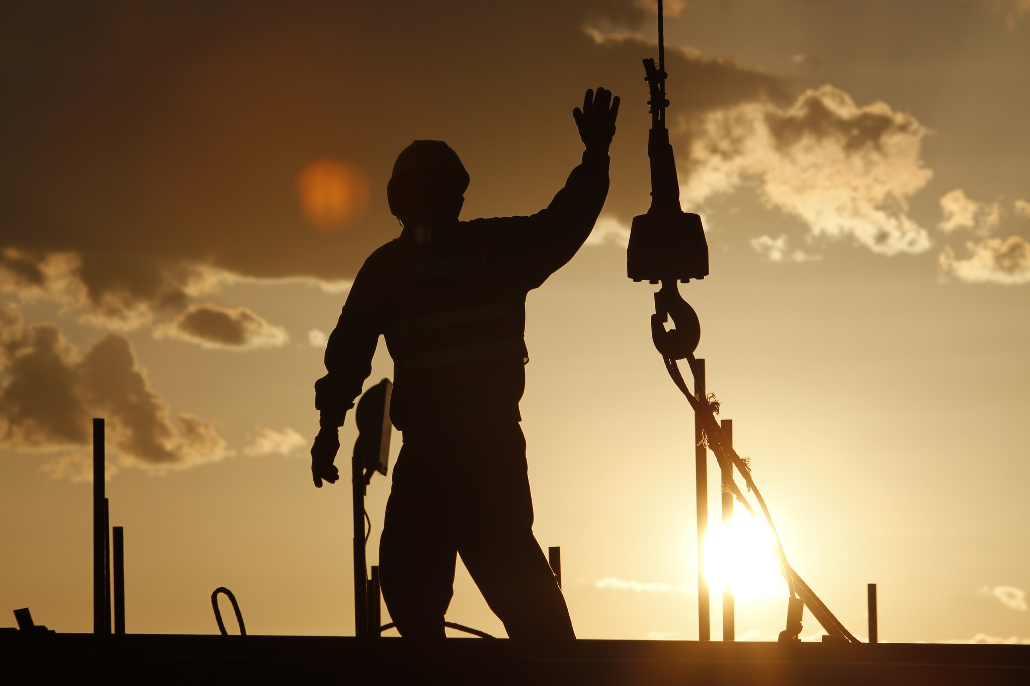A construction worker grabs the hook of a crane on a construction site. © ILO / Byamba-ochir Byambasuren 
